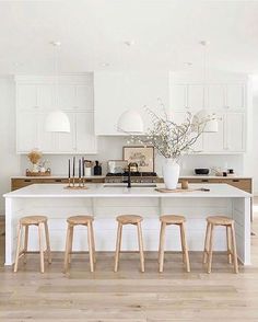 a white kitchen with stools and an island in the middle is featured on this page