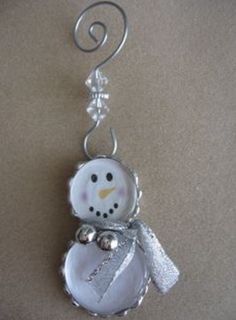 a snowman ornament hanging from a metal hook on a brown table top