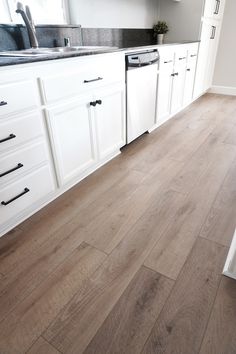 a kitchen with white cabinets and wood floors