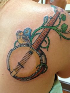 a woman with a tattoo on her back holding a musical instrument