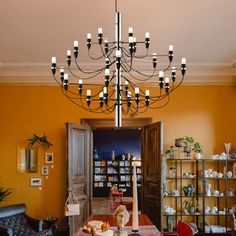 a chandelier hanging from the ceiling in a room with yellow walls and furniture