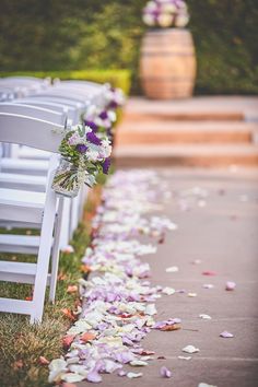 the aisle is lined with white folding chairs and purple flowers on the petals down the aisle