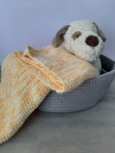 a crocheted dog in a basket with a blanket