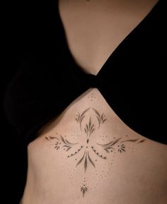 a woman's back with a tattoo design on her lower side ribcage