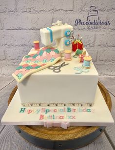 a cake that is on top of a wooden table with sewing supplies and thread spools