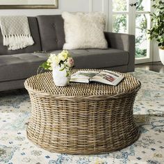 a wicker coffee table sitting on top of a rug in front of a couch