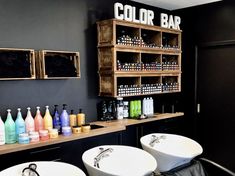 two white sinks sitting next to each other in front of a counter filled with bottles