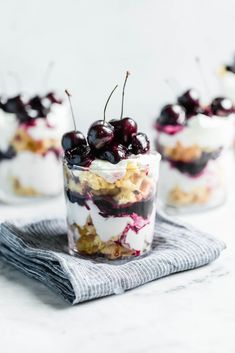 small desserts with cherries and whipped cream in glass cups on a towel, ready to be eaten