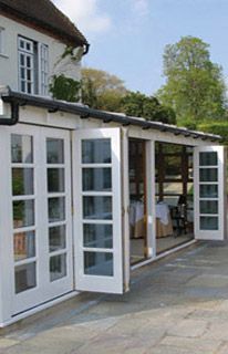 an outdoor dining area with white doors and windows