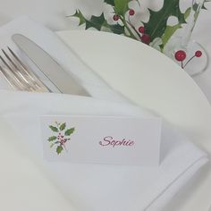 a place setting with silverware and holly decorations