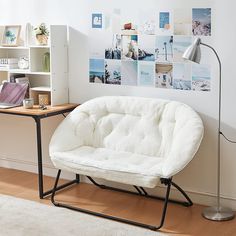 a white futon chair sitting in front of a desk with a lamp on it