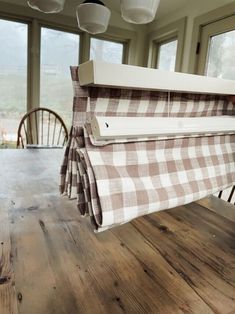 a wooden table topped with a brown and white checkered blanket