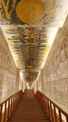 a long hallway with painted ceilings and wooden steps leading up to the second floor in an ancient building