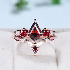 a red and white diamond ring sitting on top of a piece of cloth next to a plant