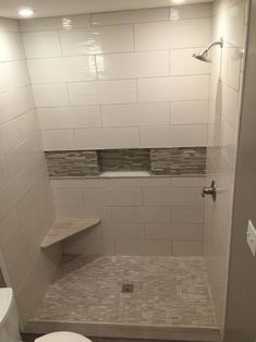 a white toilet sitting in a bathroom next to a walk in shower with tiled walls