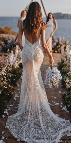 the back of a woman's dress as she walks down a path with flowers