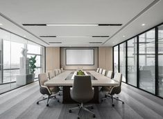 an empty conference room with chairs and a large table in front of a projector screen