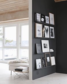 a living room with black walls and pictures on the wall next to a white bench