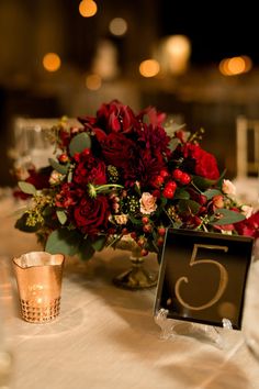 an image of a table setting with flowers and candles on it, including the number five