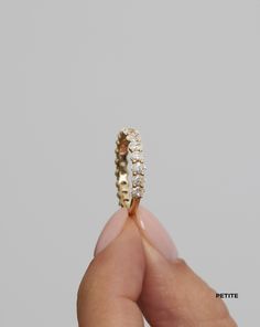 a person holding a gold ring with three diamonds on it's side and the bottom half