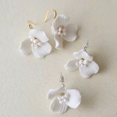 three white flower earrings on a table