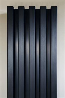 a black radiator in the corner of a room with white walls and flooring