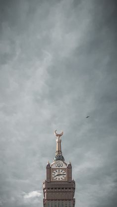 a tall clock tower sitting under a cloudy sky with a bird flying by onlookers