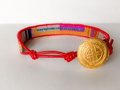 a red bracelet with a gold coin on it