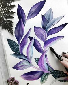 a person is drawing on paper with purple flowers and green leaves in front of them