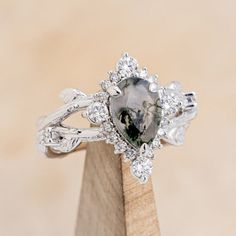 The "Artemis on the Vine Divine" is a women's engagement ring with a diamond halo and accents Center Stone: 9x6mm Pear Cut Moss Agate Accent Stones: 3/8ctw Diamond Accents (14) 1.3mm Round Diamonds (2) 1.5mm Round Diamonds (4) 2.5mm Round Diamonds Available In: 14K White Gold, 14K Yellow Gold, or 14K Rose Gold Customizable: Because each ring is handcrafted to order we can customize center or accent stones, use unique materials, customize design features, or even use your own personal materials t Moss Agate Engagement Ring, Split Shank Engagement Rings, Staghead Designs, Agate Engagement Ring, Moss Agate Ring, Mens Engagement, Pear Engagement Ring, Ring With Diamond, Ceramic Rings