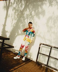 a man standing next to a wall with his hands on his face and looking at the camera