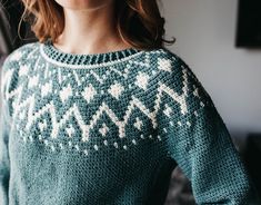 a woman wearing a green sweater with white snowflakes on it