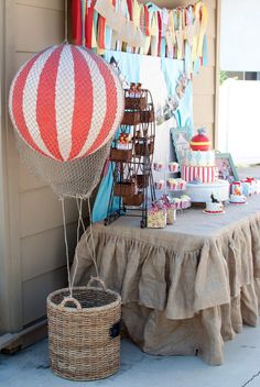 a hot air balloon sitting on top of a table next to a basket filled with cake