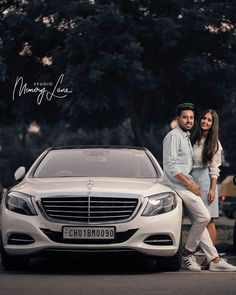 a man and woman standing next to a white car