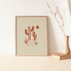 there is a small vase with some plants in it next to a framed print on the wall