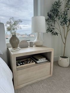 a white lamp sitting on top of a table next to a window with a tree in it