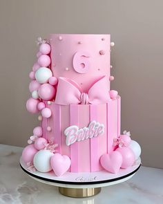 a pink birthday cake with balloons on top