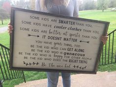 a woman holding up a sign that says some kids are smarter than you