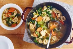 a bowl of soup with noodles, carrots and spinach