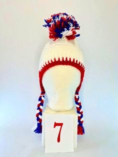 a red, white and blue knitted hat sitting on top of a wooden block