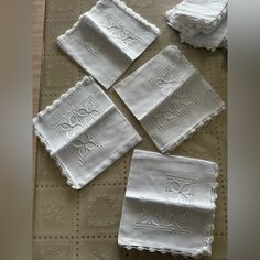 four white embroidered napkins sitting on top of a table