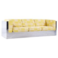 a yellow and white checkered couch sitting on top of a metal stand next to a wall