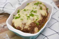 a meatloaf in a blue dish with cheese and green garnish on top