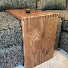 a wooden table sitting on top of a gray couch next to a grey sofa cushion