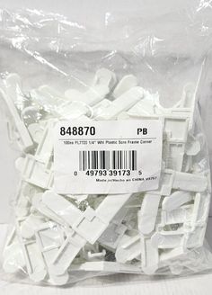 a bag of white plastic parts sitting on top of a table next to each other