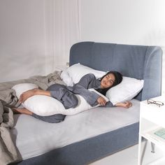 a woman laying on top of a bed with pillows