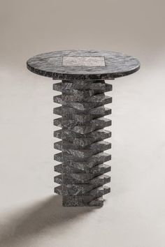 a black marble table sitting on top of a white floor next to a gray wall