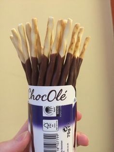 a hand holding a can filled with chocolate and vanilla sticks