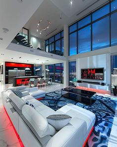 a large living room with white couches and red lights on the ceiling is lit up at night