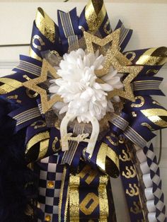 a blue and gold wreath with white flowers on it's side hanging from the front door